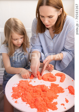 mother and daughter playing with kinetic sand. 70583167