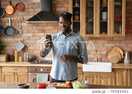 Happy biracial man talk on video call cooking at home Happy biracial man talk on video call cooking at home 70583401