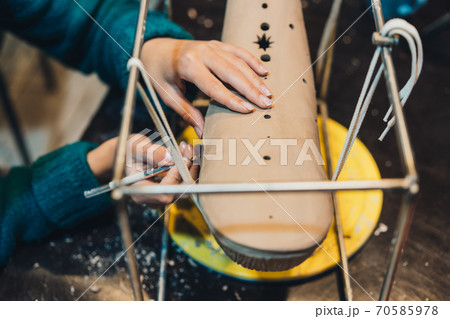 Close-up view of female hands gently handling a clay whale in workshop. 70585978