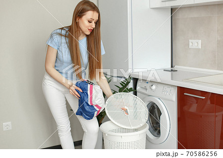 Woman uses a washing machine in the kitchen Woman uses a washing machine in the kitchen 70586256