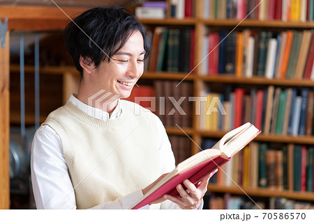 読書の秋 屋根裏部屋で本を読む笑顔の文学青年の写真素材