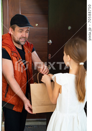 Delivery man holding a paper bag to little girl. Delivery man holding a paper bag to little girl. 70588750
