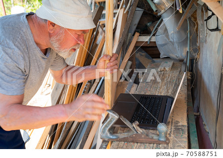 Elderly man communicates with a laptop in village Elderly man communicates with a laptop in village 70588751