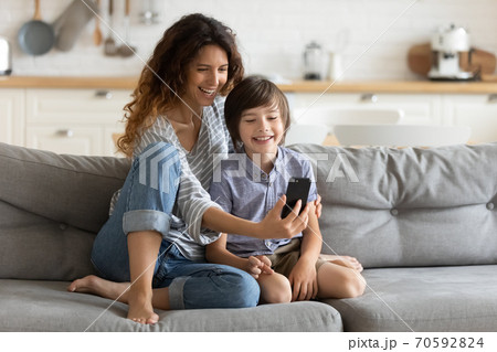 Smiling young mother and little son using phone together 70592824