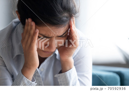 Stressed indian girl touch temples reduces unbearable headache closeup image 70592936