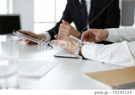 Unknown business people using tablet computer in modern office. Businessman or male entrepreneur is working with his colleague at the desk Unknown business people using tablet computer in modern office. Businessman or male entrepreneur is working with his colleague at the desk 70595134