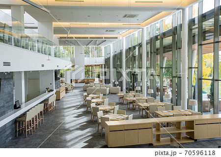 White chairs standing around square served tables and along bar counter White chairs standing around square served tables and along bar counter 70596118