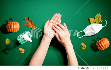 Applying sanitizer gel with autumn pumpkins and leaves 70596557