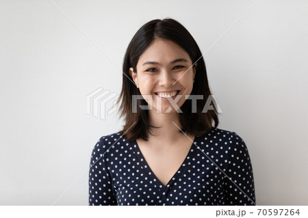 Headshot portrait of smiling asian woman isolated on grey wall Headshot portrait of smiling asian woman isolated on grey wall 70597264