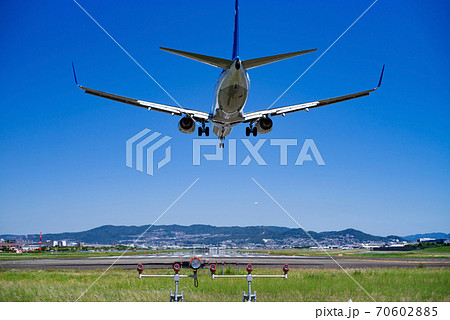 大阪府豊中市千里川堤防土手 着陸する飛行機と青空の広がる伊丹空港の写真素材