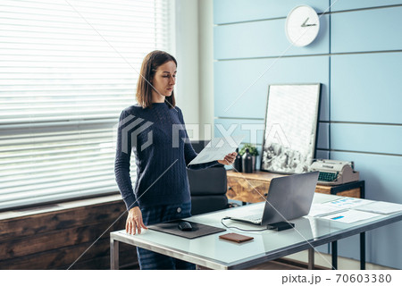 Woman stands with paper in her hand and looks over the information. Woman stands with paper in her hand and looks over the information. 70603380