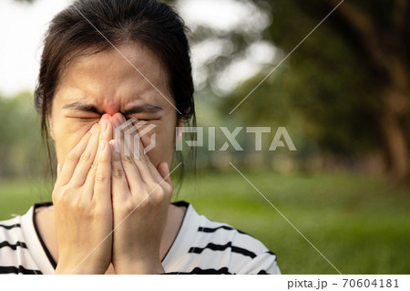Sad asian young woman holding her nose with closed eyes while paranasal sinus pain,sinusitis symptoms or dust allergies, unhealthy female person with sinus pressure,nasal disease, health care concept 70604181