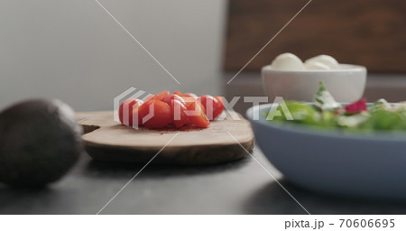 Closeup man takes tomato halves from olive wood Closeup man takes tomato halves from olive wood 70606695