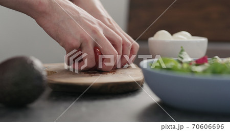 Closeup man takes tomato halves from olive wood Closeup man takes tomato halves from olive wood 70606696