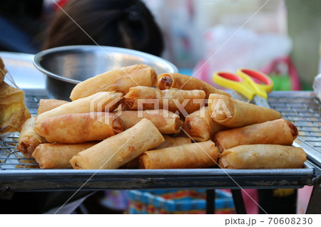Heap of fried spring rolls place on the stainless grill and tray. 70608230