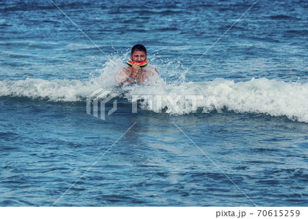 Caucasian man eating piece of watermelon in the sea water Selective focus 70615259