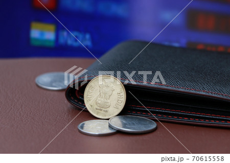 The brass coin of India Rupee money and black leather wallet on brown floor with digital board The brass coin of India Rupee money and black leather wallet on brown floor with digital board 70615558