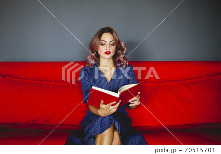 Woman reading book on couch 70615701