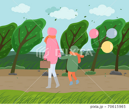 Mom and child with balls walking in autumn park, cold windy weather, trees are sloping from wind 70615965