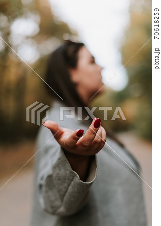 Beautiful woman in a gray coat on an autumn alley. Blurry portrait of a woman 70618259
