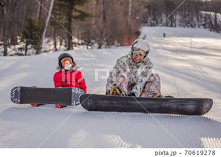 Dad teaches son snowboarding. Activities for children in winter. Children's winter sport. Lifestyle Dad teaches son snowboarding. Activities for children in winter. Children's winter sport. Lifestyle 70619278