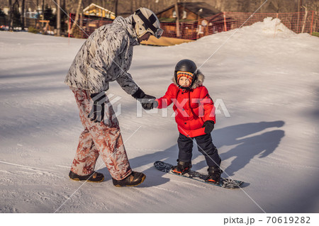 Dad teaches son snowboarding. Activities for children in winter. Children's winter sport. Lifestyle 70619282