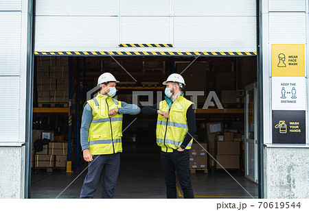 Workers with face mask greeting in front of warehouse, coronavirus concept. 70619544