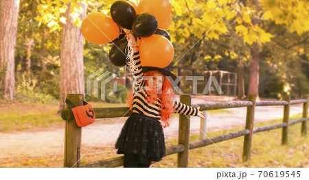 Little girl in the autumn park. A child in a witch costume on Halloween with large colored balloons 70619545