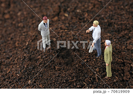 土の上で話し合うビジネスマンたち 70619909