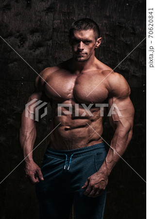 Sporty and healthy muscular man on dark grunge background Sporty and healthy muscular man on dark grunge background 70620841