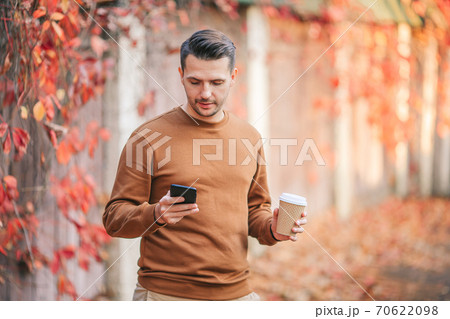 Young man drinking coffee in autumn park outdoors 70622098