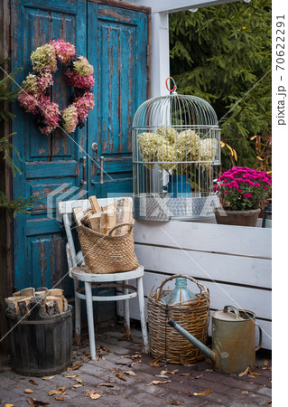 Autumn garden decoration set near the house, hydrangea wreath, old instruments, colorful flowers potted 70622291