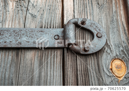Metal door hinge with torn nails, on an old wooden gate Metal door hinge with torn nails, on an old wooden gate 70625570