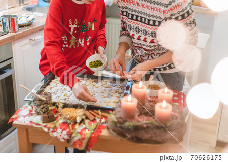 Mother and son decorating Christmas cookies on the sheet 70626175