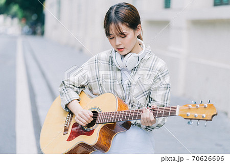 woman playing guitar on the street 70626696