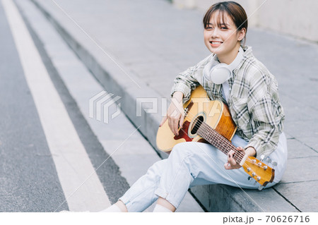 woman playing guitar on the street 70626716