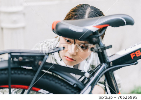 Woman self-repairs her bike Woman self-repairs her bike 70626995