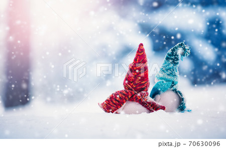 Little snowmans on soft snow on blue background in snowfall Little snowmans on soft snow on blue background in snowfall 70630096