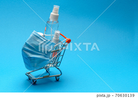 protective masks and antibacterial disinfection sanitizer gel in a small shopping trolley cart on blue background with copy space protective masks and antibacterial disinfection sanitizer gel in a small shopping trolley cart on blue background with copy space 70630139