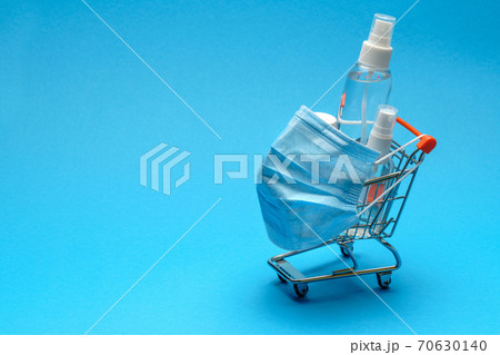 protective masks and antibacterial disinfection sanitizer gel in a small shopping trolley cart on blue background with copy space protective masks and antibacterial disinfection sanitizer gel in a small shopping trolley cart on blue background with copy space 70630140