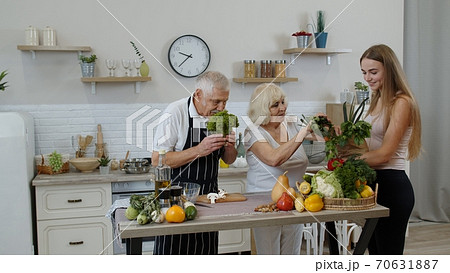Elderly couple in kitchen receiving vegetables from grandchild. Raw food healthy eating diet Elderly couple in kitchen receiving vegetables from grandchild. Raw food healthy eating diet 70631887