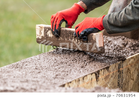 Construction Worker Leveling Wet Cement Into Wood Framing 70631954