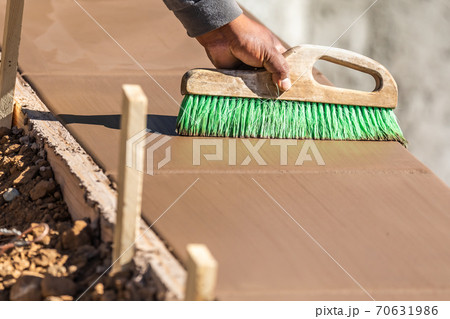 Construction Worker Using Brush On Wet Cement Forming Coping Around New Pool 70631986