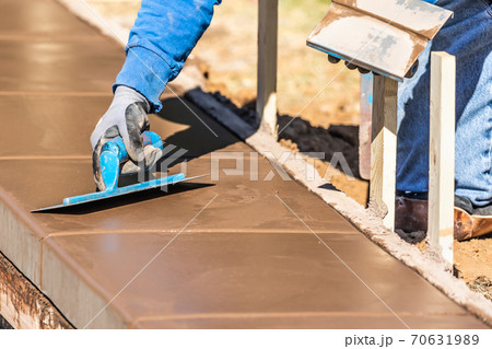 Construction Worker Using Trowel On Wet Cement Forming Coping Around New Pool Construction Worker Using Trowel On Wet Cement Forming Coping Around New Pool 70631989