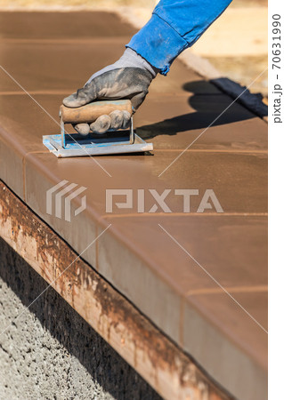 Construction Worker Using Hand Groover On Wet Cement Forming Coping Around New Pool Construction Worker Using Hand Groover On Wet Cement Forming Coping Around New Pool 70631990