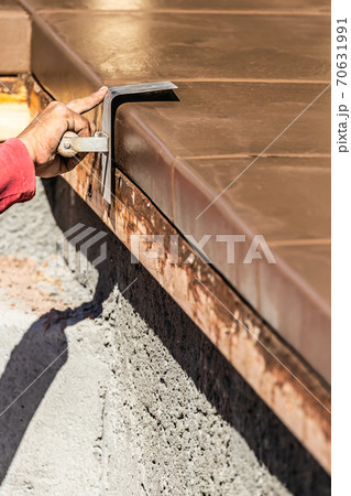 Construction Worker Using Stainless Steel Edger On Wet Cement Forming Coping Around New Pool 70631991