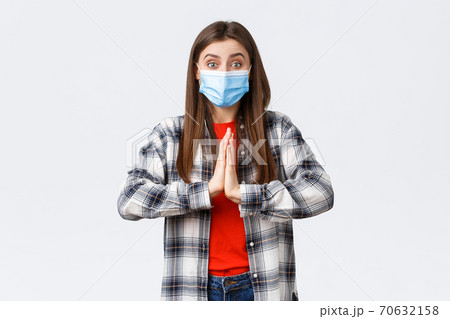 Different emotions, covid-19 pandemic, coronavirus self-quarantine and social distancing concept. Hopeful enthusisatic girl, volunteer in medical mask, asking please, begging help, hold hands in pray 70632158