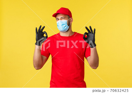 Express delivery during pandemic, covid-19, safe shipping, online shopping concept. Courier ensure and promise best and fast package, order delivery, wink and camera show okay sign 70632425