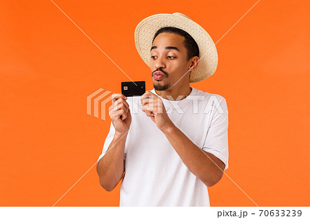 Guy likes wasting money, buying tickets for valentines day gift girlfriend, trip luxury resort, kissing credit card as using cashback, deposit money, saved cash for travel, orange background 70633239