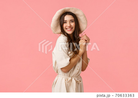 Feminine, coquettish and flirty woman with dark curly hair, wearing trendy hat and stylish dress, laughing, enjoying beautiful romantic date, clap hands and gazing camera delighted, pink background 70633363
